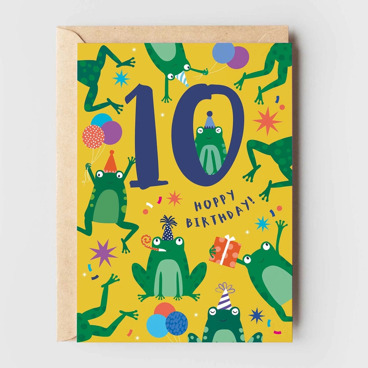 Greeting card featuring illustrations of frogs wearing party hats and holding balloons on a yellow background. The text '10' and 'Happy Birthday!' are printed on the centre of the card. 