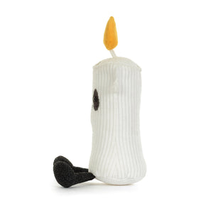 Side view of a white corduroy candle plush toy with a yellow-orange flame on top. It has a black mouth and eyes, black sparkly patches around it's eyes and black feet. It is shown on a white background. 