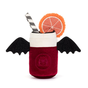 Back view of a plush toy shaped like a can of pop dressed like a vampire. The plush features a deep red velvet body, a white top, black bat wings, a black-and-white striped straw, and a decorative orange slice garnish. The plush is shown on a white background.
