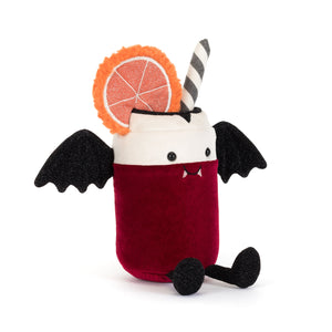 A plush toy shaped like a can of pop dressed like a vampire with fangs. The plush features a deep red velvet body, a white top, black bat wings, a black-and-white striped straw, and a decorative orange slice garnish. The plush is shown on a white background.