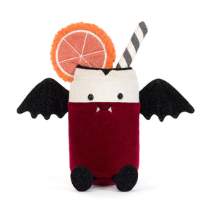 A plush toy shaped like a can of pop dressed like a vampire with fangs. The plush features a deep red velvet body, a white top, black bat wings, a black-and-white striped straw, and a decorative orange slice garnish. The plush is shown on a white background.
