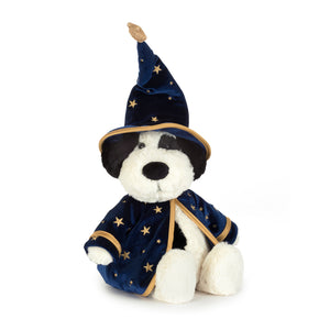 A plush black and white dog toy dressed as a wizard, featuring a navy blue velvet robe and pointed hat with gold star patterns and trim, set against a plain white background.