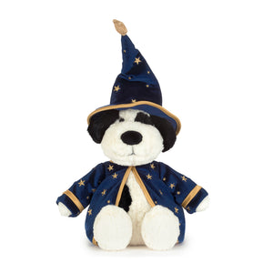 A plush black and white dog toy dressed as a wizard, featuring a navy blue velvet robe and pointed hat with gold star patterns and trim, set against a plain white background.