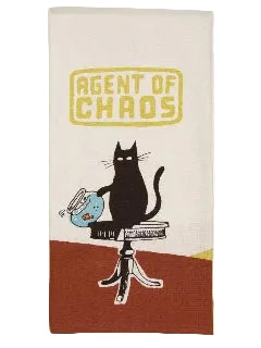 A white kitchen towel featuring a retro-style illustration of a black cat sitting on a table and knocking over a blue fishbowl, with the text 'AGENT OF CHAOS' in yellow above. The bottom of the towel has a rust-brown block background.