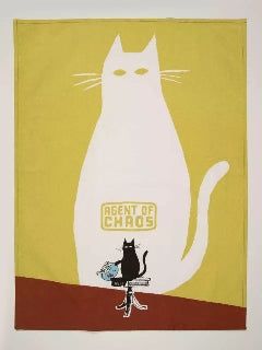Kitchen towel featuring a retro-style illustration of a black cat sitting on a table and knocking over a blue fishbowl, with the text 'AGENT OF CHAOS' in yellow above. A white cat-shaped shadow is shown on the green wall behind the cat, while the bottom of the towel has a rust-brown block background.