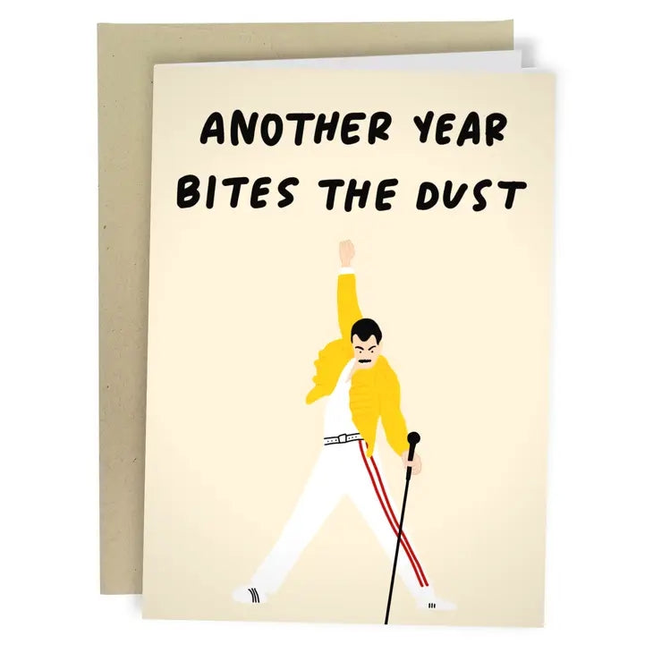 Greeting card with an illustration of Freddie Mercury holding a microphone and dancing on a light coloured background. The text 'Another Year Bites The Dust' is printed on the top of the card.