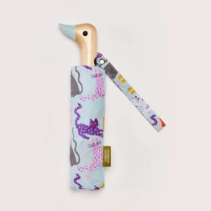 Blue umbrella with an abstract cat print with a wooden duck head shaped handle on a white background. 