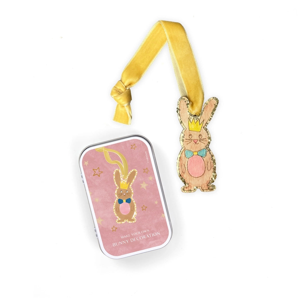 Decorative bunny ornament with a yellow ribbon beside pink packaging.