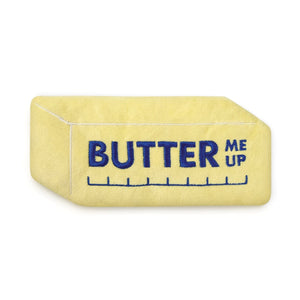 A yellow comfort eye mask in the shape of a stick of butter shown on a white background. The eye mask shows the text 'Butter Me Up'.
