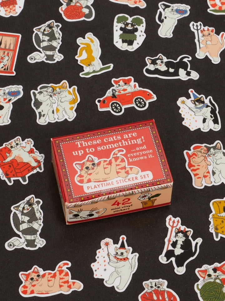 Image showing a packaging box for a cat-themed sticker set. Stickers of mischevious cats surround the box. The box and stickers sit against a black surface.