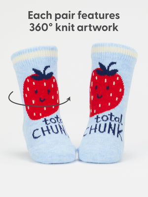 A pair of light blue socks featuring a print of a red strawberry with a smiling face and the text 'total chunk'. The text 'Each pair features 360° knit artwork' is printed above the socks on a white background. 