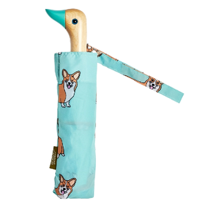 Blue umbrella with a corgi print and a wooden duck head shaped handle on a white background.