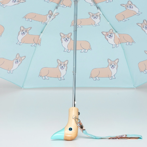 Opened inside view of a blue umbrella with a corgi print and a wooden duck head shaped handle on a white background.