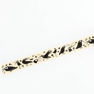 A close-up of an opened washi tape featuring black crow illustrations on a cream background.The tape is shown against a white background. 
