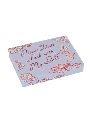 Image of a light purple pocket-sized storage tin featuring an illustration of a a fairy waving a magic wand over the text 'Please Don't Fuck With My Shit'. Illustrations of pink flowers surround the text too. The tin sits on a white background. 