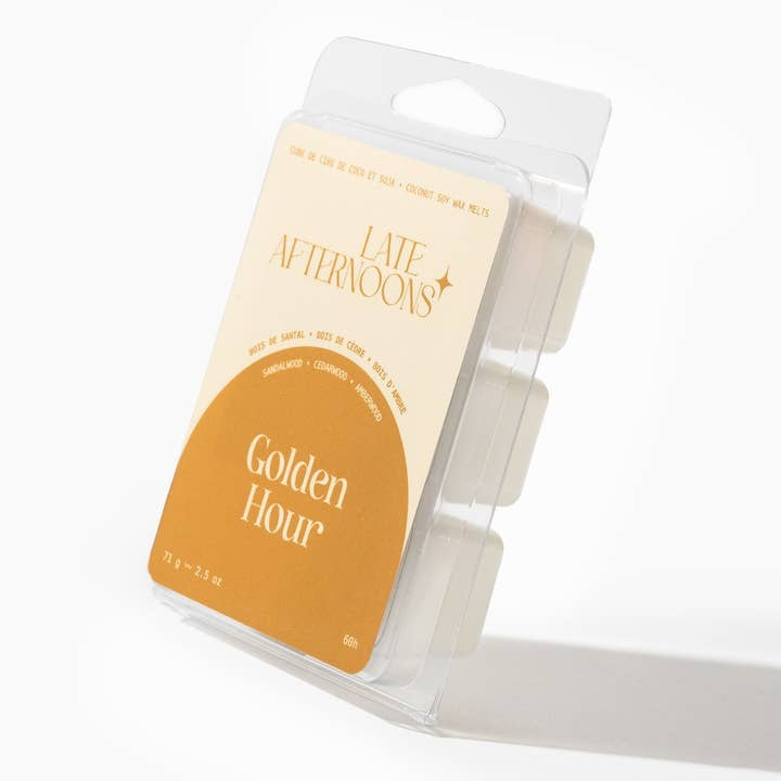 A packaged wax melt product with label that shows the brand name and the text 'Golden Hour' with a warm beige and tan color scheme. The package sits on a white background. 