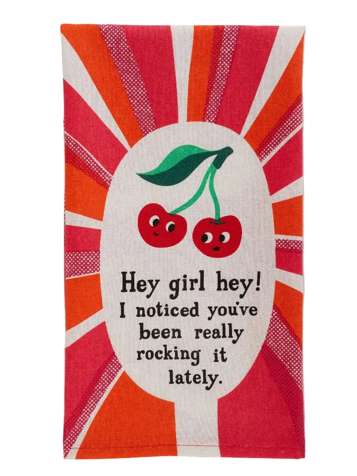 Kitchen towel featuring an illustrated image of smiling cherries on a white, red and orange background. The text 'Hey girl hey! I noticed you've been really rocking it lately.' is printed in the centre of the towel, under the cherries. 