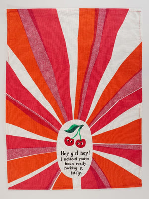 Kitchen towel featuring an illustrated image of smiling cherries on a white, red and orange background. The text 'Hey girl hey! I noticed you've been really rocking it lately.' is printed on the towel, under the cherries. 