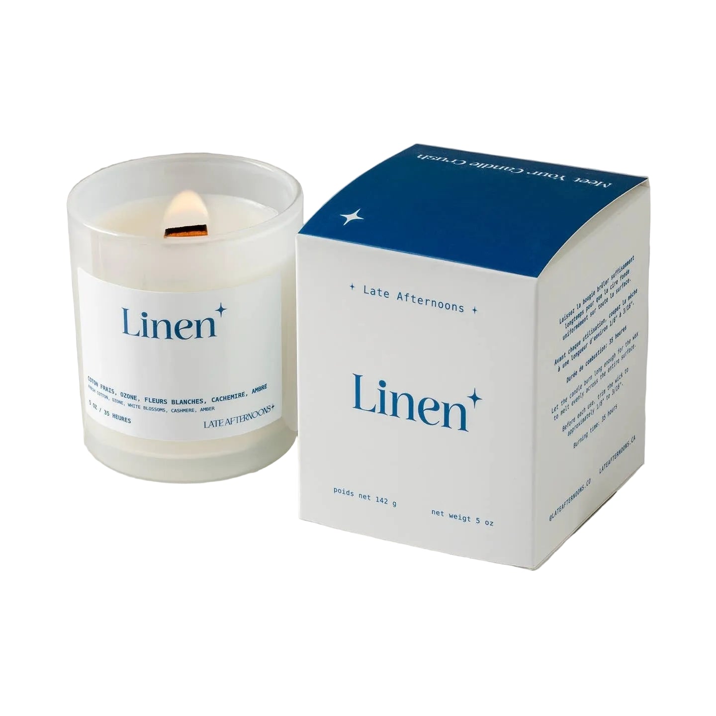A candle in a milky-white glass jar filled with white wax and a lit wick. The candle sits next to a dark blue and light blue packaging box on a white background. The text 'Linen' is printed on both the candle and box, along with the company branding. 
