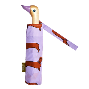Purple umbrella with an abstract weiner design and a wooden duck head shaped handle on a white background. 