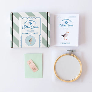 Cross-stitch kit with an embroidery hoop, an instruction booklet, and packaging on a white background.