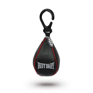 The image shows a black punch bag shaped hanging baby toy attached to a clip. A red tag in the shape of a boxing glove shows the company branding and text 'Buff Baby'. The hanging toy sits on a white background. 