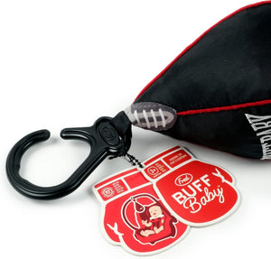 Close up of the top of a black punch bag shaped hanging baby toy attached to a clip. A red tag in the shape of a boxing glove shows the company branding and text 'Buff Baby'. The hanging toy sits on a white background. 