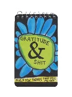 A spiral-bound notebook with a black cover featuring a large flower with blue petals and a green centre that reads 'Gratitude & Shit' in black text.