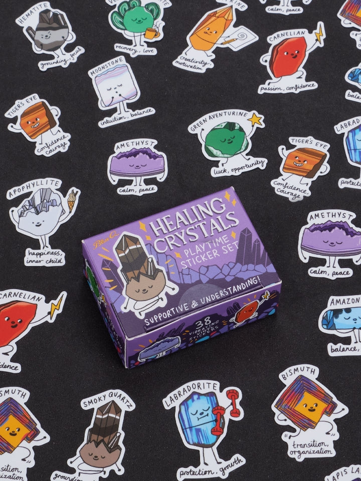 Image showing a packaging box for a Healing Crystals themed sticker set. Stickers of colourful crystals with faces surround the box. The box and stickers sit against a black surface.