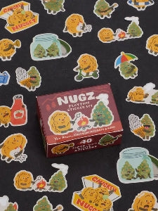 Image showing a packaging box for a Nugz-themed sticker set. Stickers of  chicken nuggets and cannabis nugs with faces surround the box. The box and stickers sit against a black surface.