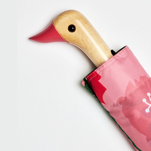 Closeup of the top half of a Pink umbrella with a wooden duck head shaped handle on a white background. 