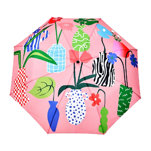 Open view of a pink umbrella with an abstract plant and vase design on a white background. 